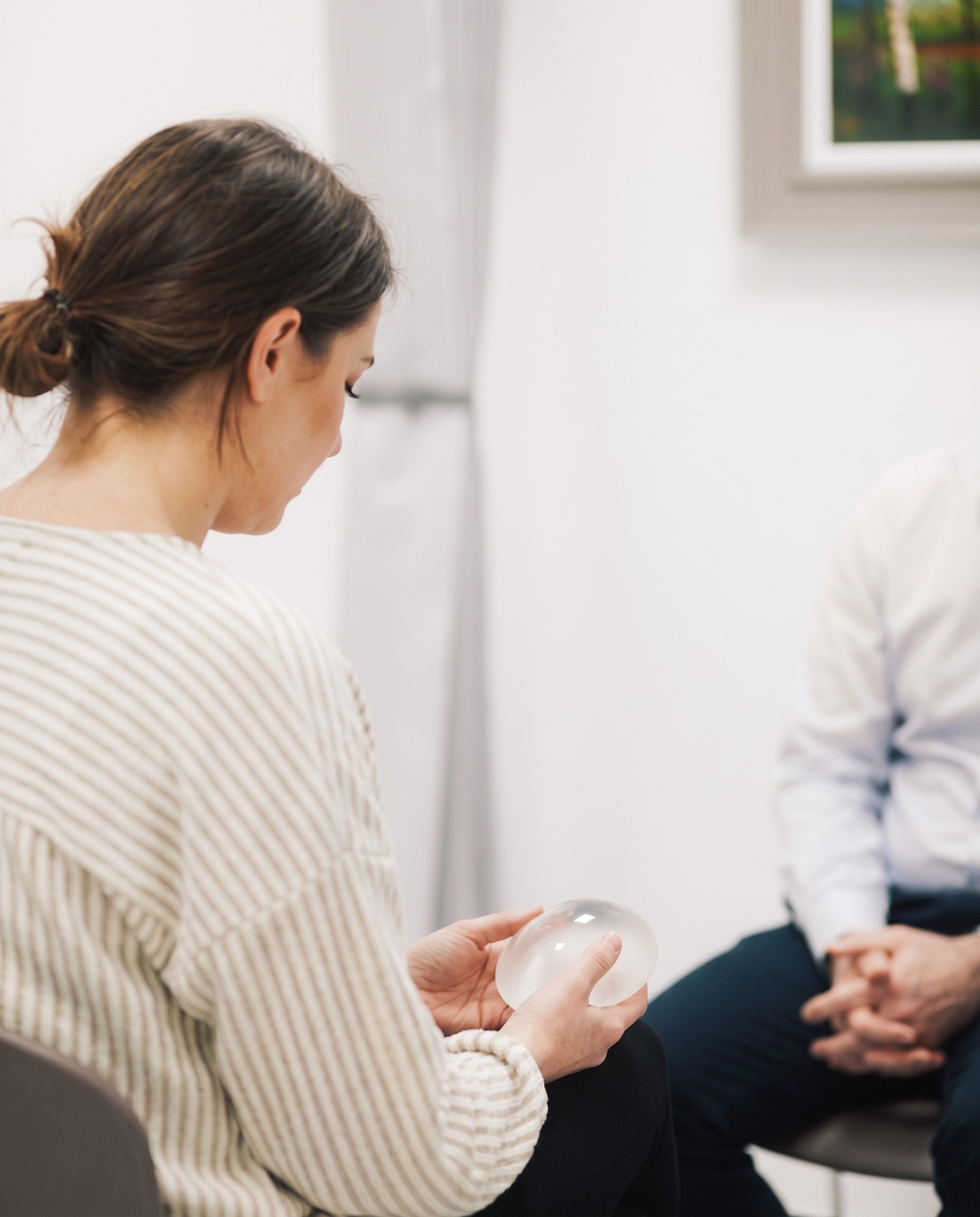 Patient holding a breast implant sizer during her consultation